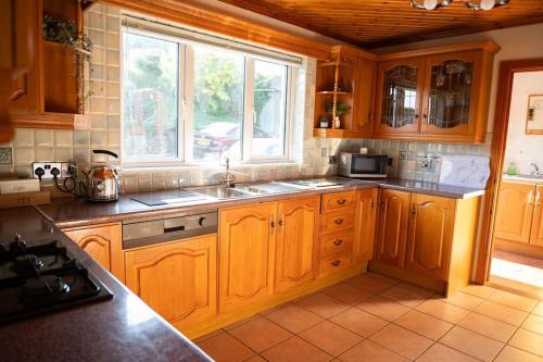 a kitchen with wooden cabinets and a sink and a window at The Scotch Rock in Castlewellan
