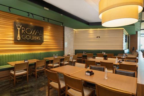 a restaurant with tables and chairs and a sign on the wall at Royal Macaé Palace Hotel in Macaé