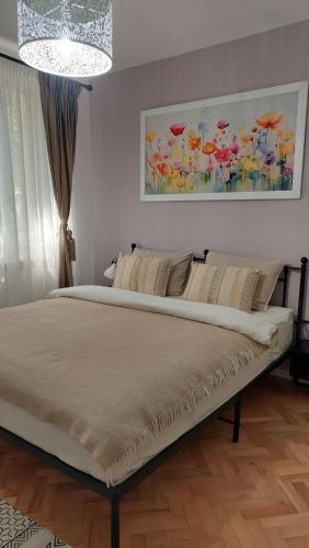 a bed in a bedroom with a painting on the wall at Helen Apartament in Craiova