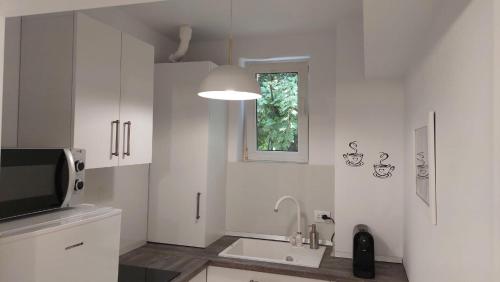 a white kitchen with a sink and a window at Helen Apartament in Craiova