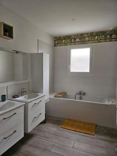 La salle de bains est pourvue d'une baignoire, de 2 lavabos et d'une fenêtre. dans l'établissement Jolie maison neuve avec piscine, à Esnandes