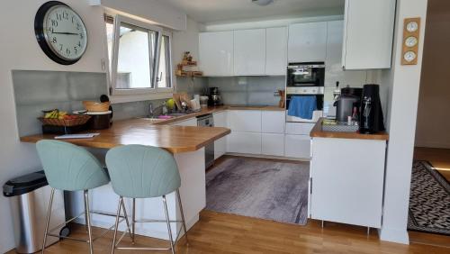 une cuisine avec un comptoir et une horloge au mur dans l'établissement Villa avec piscine By Platinum Homes- capacité 8 personnes - Heillecourt, à Heillecourt