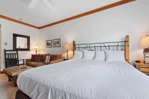 Un dormitorio con una gran cama blanca y un sofá. en The Charter at Beaver Creek D225, en Beaver Creek