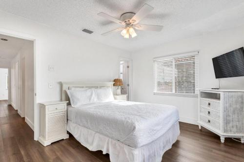 a white bedroom with a bed and a ceiling fan at Beach Trail Bungalow Triplex in Clearwater Beach