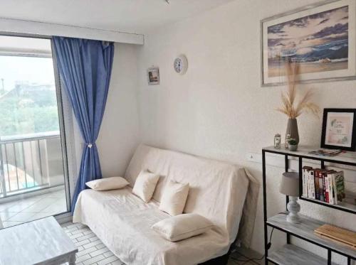 un salon avec un canapé et une fenêtre dans l'établissement Appart lumineux Piscine Parking, au Cap d'Agde
