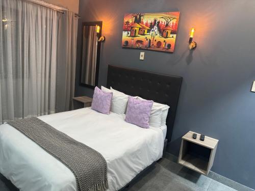 a bedroom with a large bed with purple pillows at Kv Luxury Guest House in Johannesburg