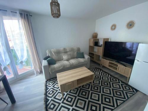 un salon avec un canapé et une télévision à écran plat dans l'établissement Studio en bord de mer 200M, à Fréjus