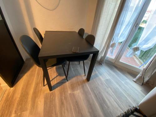 - une table et des chaises noires dans une chambre avec fenêtre dans l'établissement Studio en bord de mer 200M, à Fréjus