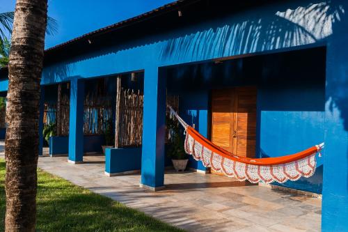 a blue house with a hammock in front of it at Vila Kavaju Preá in Prea