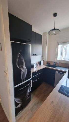 Il comprend une cuisine équipée d'un réfrigérateur avec un tableau. dans l'établissement Appartement en bord de plage - à 50 m de la mer, à Canet