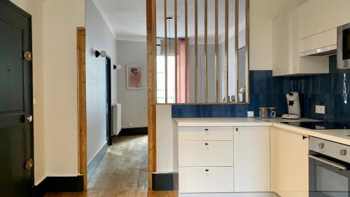 une cuisine avec des placards blancs et du carrelage bleu dans l'établissement L'escapade rêvée, à Nevers