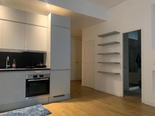 une cuisine avec des armoires blanches et un four à plaques de cuisson dans l'établissement Two-bed apartment - Saint-Lazare, à Paris
