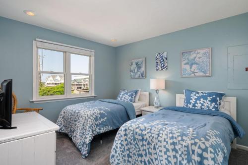 een blauwe slaapkamer met 2 bedden en een raam bij SNH249 SeaAira in Nags Head