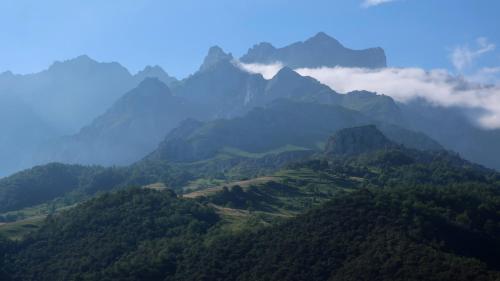 a view of a mountain range with clouds and trees at Casa Vacacional La Pedrera in Baró