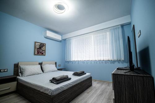 a blue bedroom with a bed and a television at Апартамент за гости НЕЛИТА in Varshets