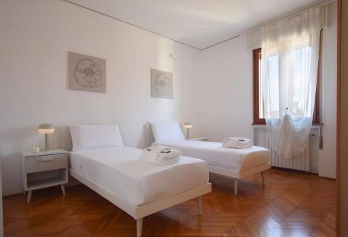 two beds in a white room with a window at Welc-oM Deluxe next to Pra della Valle in Padova