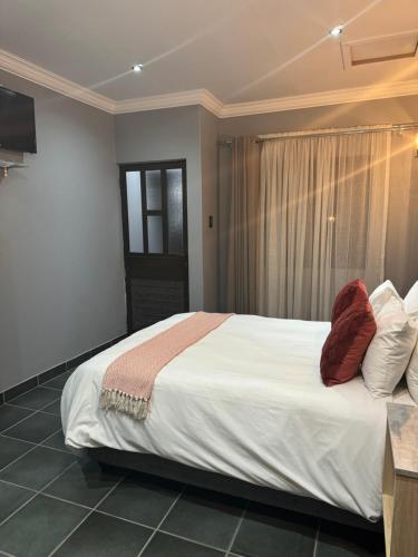 a bedroom with a large white bed with red pillows at Kv Luxury Guest House in Johannesburg