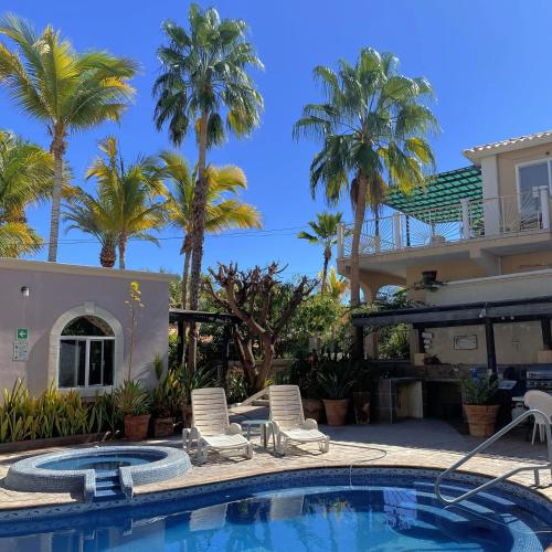 a swimming pool with two chairs and palm trees at Casa Grande - Coco Cabanas Loreto in Loreto