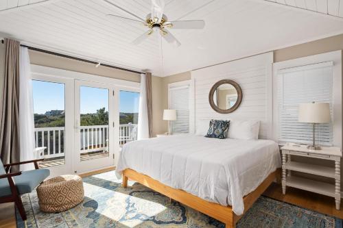 a white bedroom with a bed and a balcony at SH125 Here & Now in Southern Shores