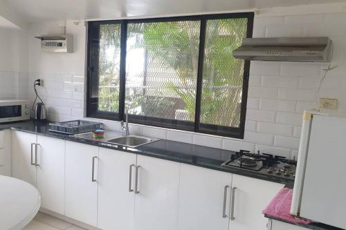 a white kitchen with a sink and a window at Kianna Apartments in Mba