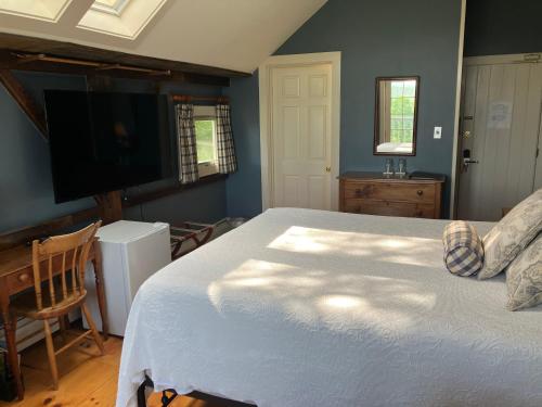 a bedroom with a bed and a flat screen tv at Windham Hill Inn in West Townshend