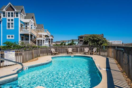 a swimming pool with chairs and a fence at SC04 Sand Castle 4 in Kill Devil Hills