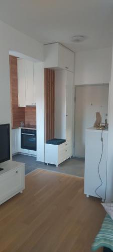 an empty kitchen with white cabinets and a television at Apartman Oaza Tuzla in Tuzla
