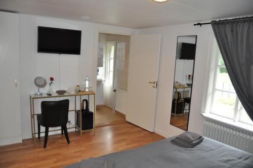 a bedroom with a bed and a desk and a television at Långstorp 200 Gästhem i Höör vänster in Höör