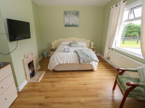 a bedroom with a bed and a tv on the wall at Kate's Cottage in Ballina