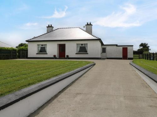 a white house with red doors and a driveway at Kate's Cottage in Ballina