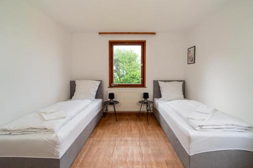 two beds in a room with a window at RANGE - Landhaus mit Panoramablick - 2 Apartments - Parkplatz - Küche - WLAN - Monteure 1-11 Personen in Winterbach