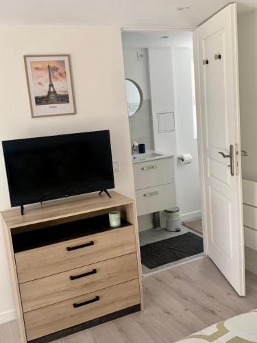- un salon avec une télévision sur une commode en bois dans l'établissement 'StudioCDG fr' Jardin, Studio proche near CDG Roissy airport, Parc Expositions, Stade de France, Arena, Disney, Asterix, à Villepinte