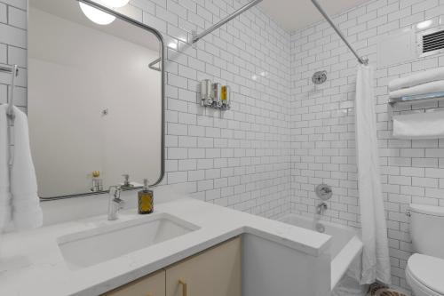 a white bathroom with a sink and a mirror at Norblad Hotel in Astoria, Oregon