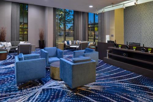 a hotel lobby with blue chairs and tables at Courtyard by Marriott Wilmington Downtown/Historic District in Wilmington