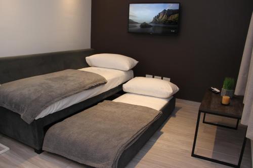 two beds in a room with a tv on the wall at In House BA - Le coq in Buenos Aires