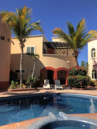 a house with a swimming pool and palm trees at Coco Cabanas Loreto in Loreto