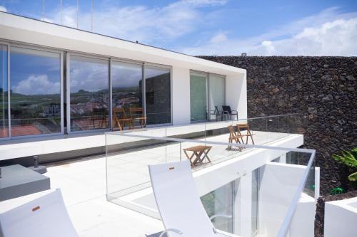 a glass house with chairs on the balcony at Casa Neptuno-Lagoa São Miguel in Lagoa