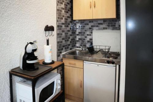 une petite cuisine avec un micro-ondes et un évier dans l'établissement Résidence Orr Des Neiges - LES ORRES 1650 coeur de station MAE-7501, aux Orres