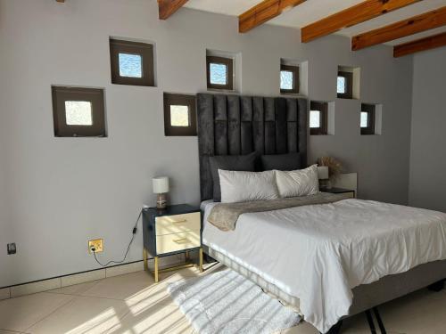 a bedroom with a large bed with a black headboard at Amari Cottage in Boksburg