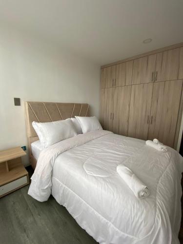 a bedroom with a large bed with white sheets and pillows at Hermoso apartamento central nuevo in Pasto