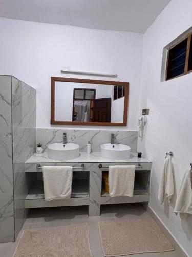 a bathroom with two sinks and a mirror at Nungwi Beach Front in Nungwi