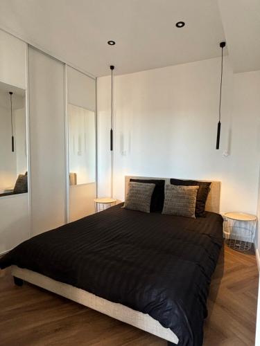 - une chambre avec un grand lit noir et 2 tables dans l'établissement Appartement cosy, à Bagnols-en-Forêt