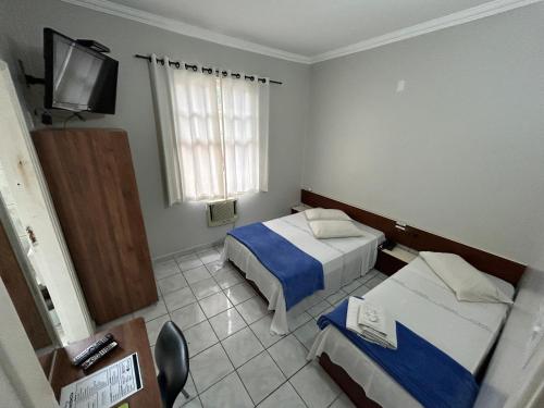 a hotel room with two beds and a television at Caiçara Hotel in Santos
