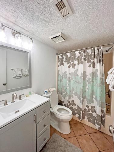 a bathroom with a toilet and a sink and a mirror at Seaside Orange Beach, Gulf Front, Tennis, and Pools! in Orange Beach