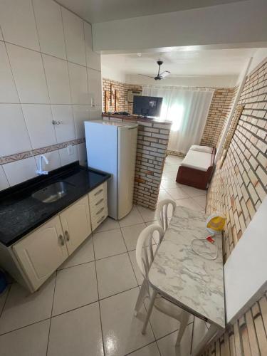 a small kitchen with a table and a refrigerator at Pousada Ramo de Acácia in Bombinhas