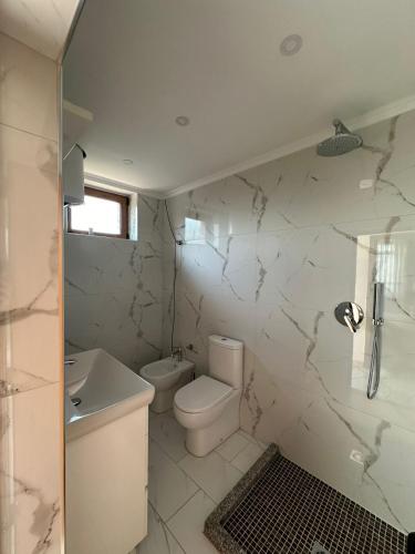 a white bathroom with a toilet and a sink at The Cuni Castle in Shkodër