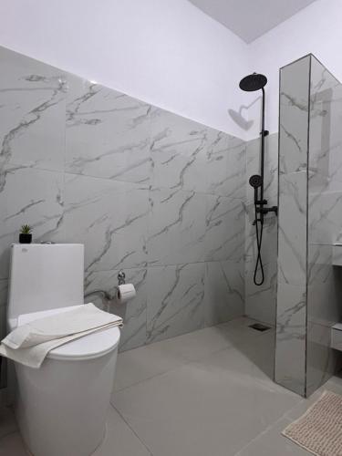 a white bathroom with a toilet and a shower at Nungwi Beach Front in Nungwi