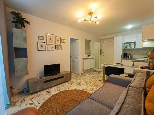 - un salon avec un canapé et une télévision dans l'établissement La Résidence Fleuries - Plage, à Cannes