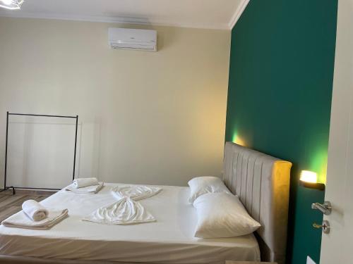 a bed in a room with a green wall at Grandfather Superior Apartment in Berat