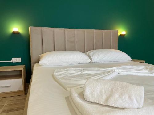 a bed with white sheets and pillows in a room at Grandfather Superior Apartment in Berat